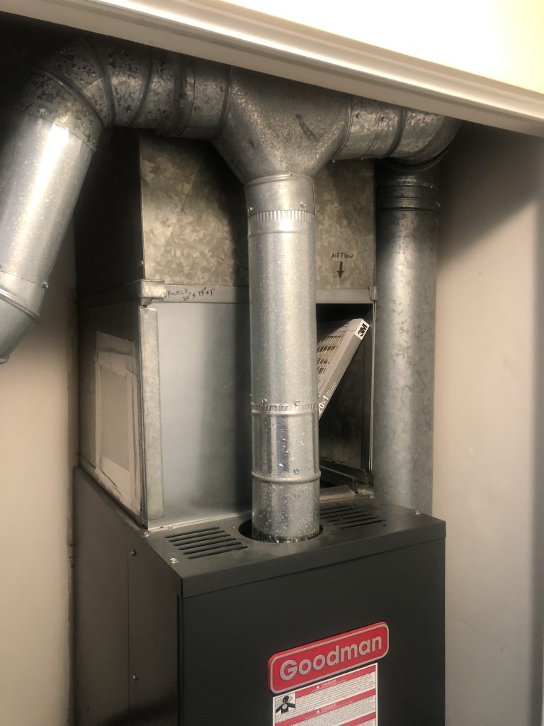 Goodman gas furnace with metal ductwork and an open filter rack during an Auburn furnace repair