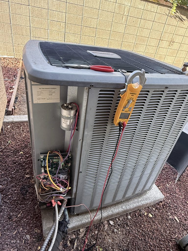 Outdoor AC unit with the service panel open, capacitor and clamp meter during a Loomis, CA repair