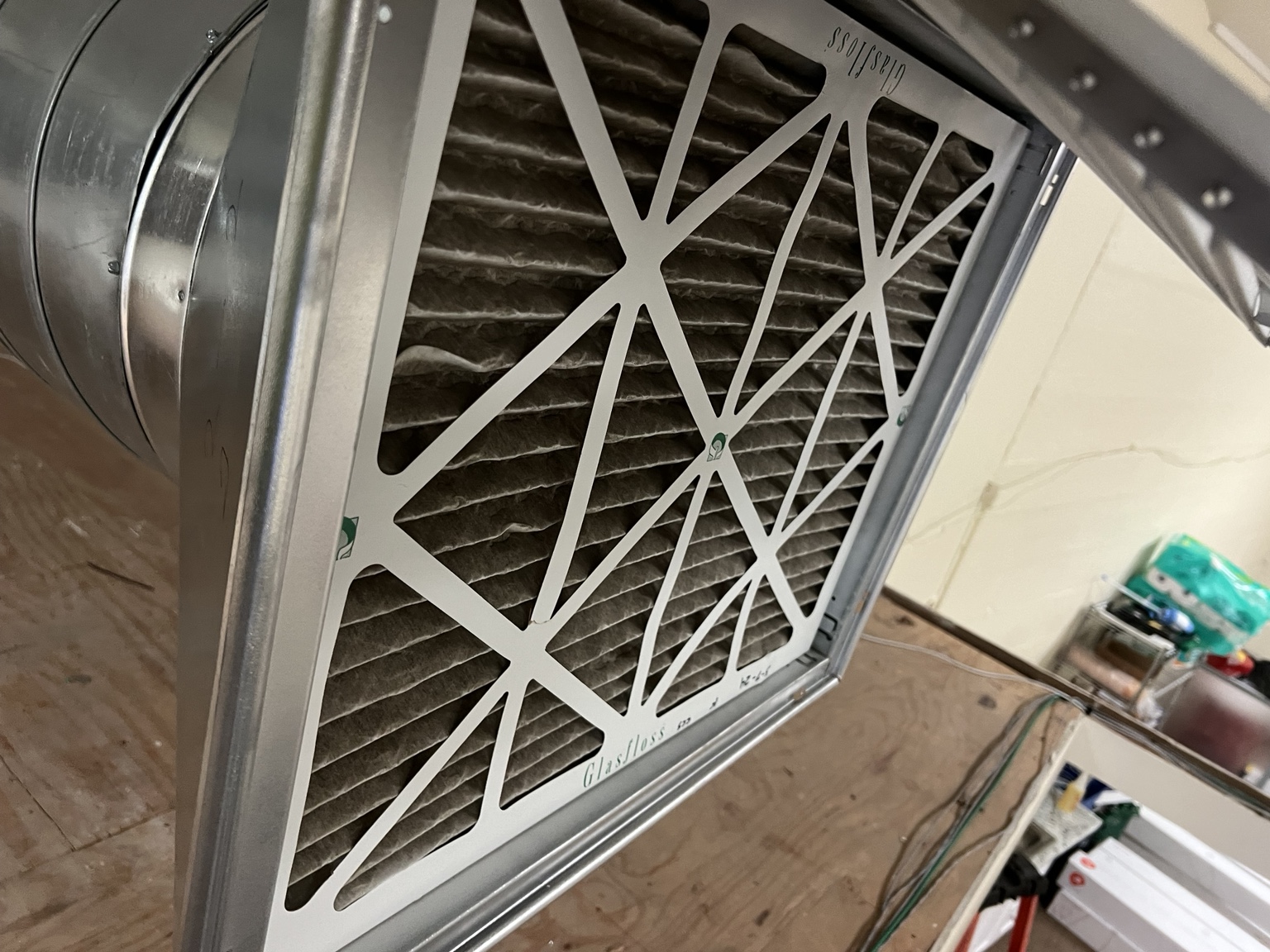 Dirty pleated HVAC air filter with visible dust buildup in a return grille