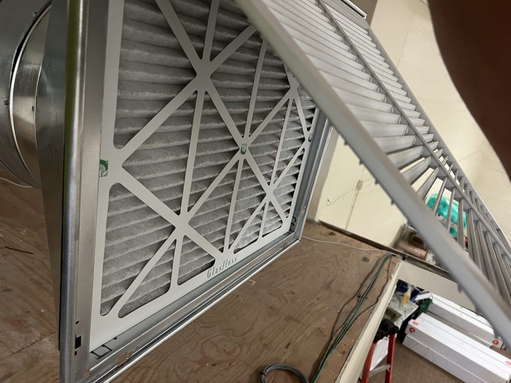 Clean replacement HVAC air filter installed behind an open return grille