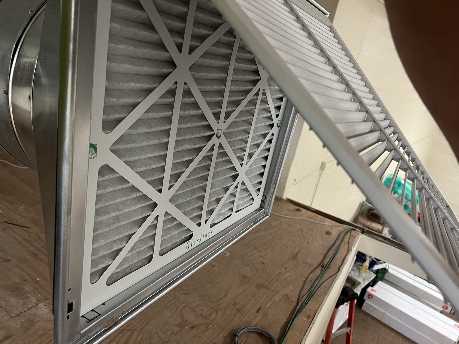 Clean replacement HVAC air filter installed behind an open return grille