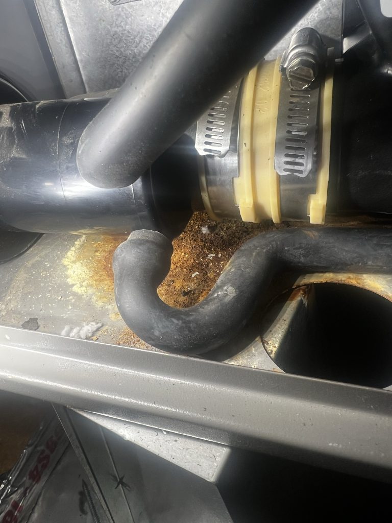 Furnace hose connection and rust-stained cabinet surface photographed during the Newcastle service call