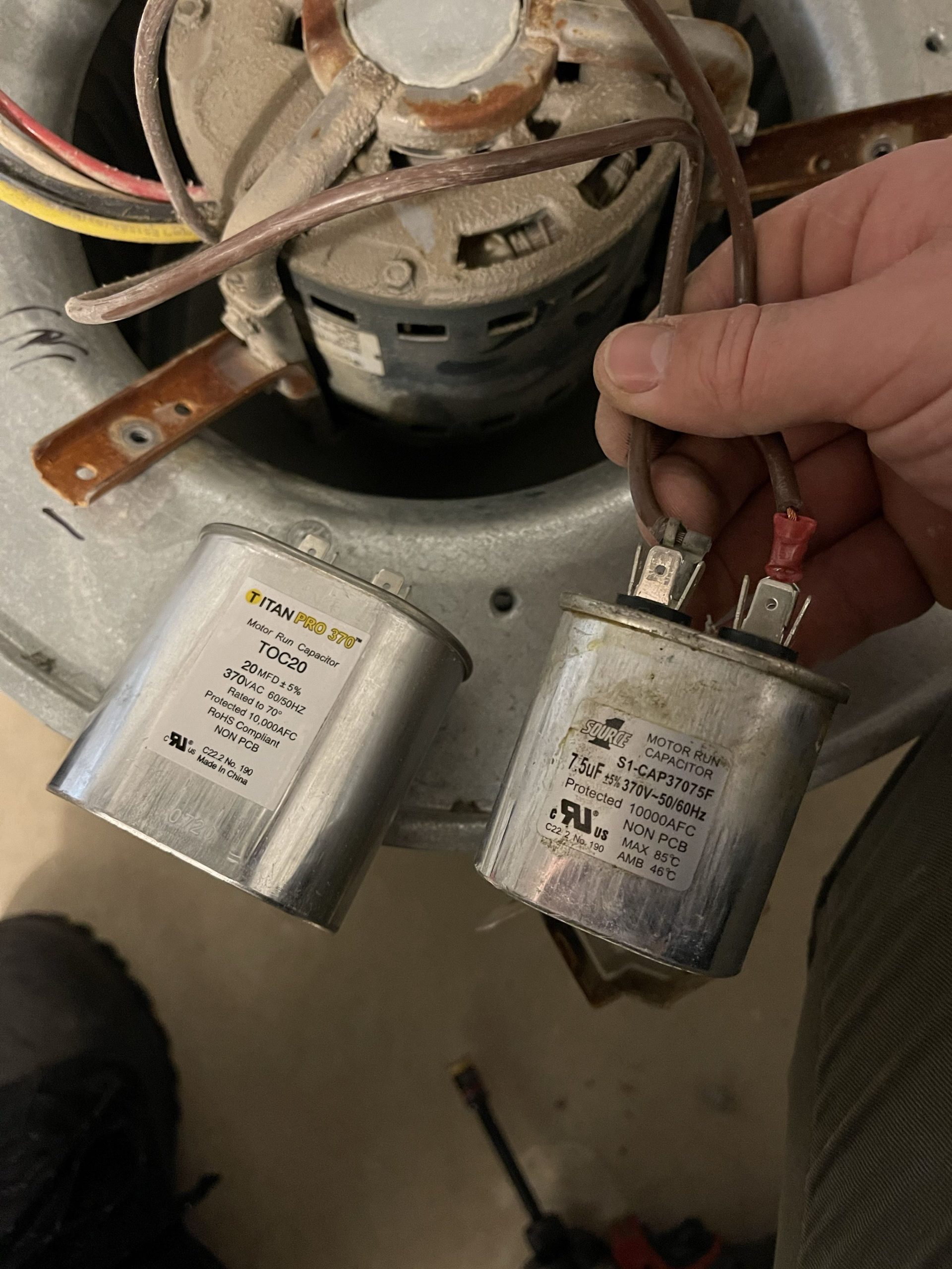 Motor run capacitors beside a furnace blower assembly during a Roseville heating repair