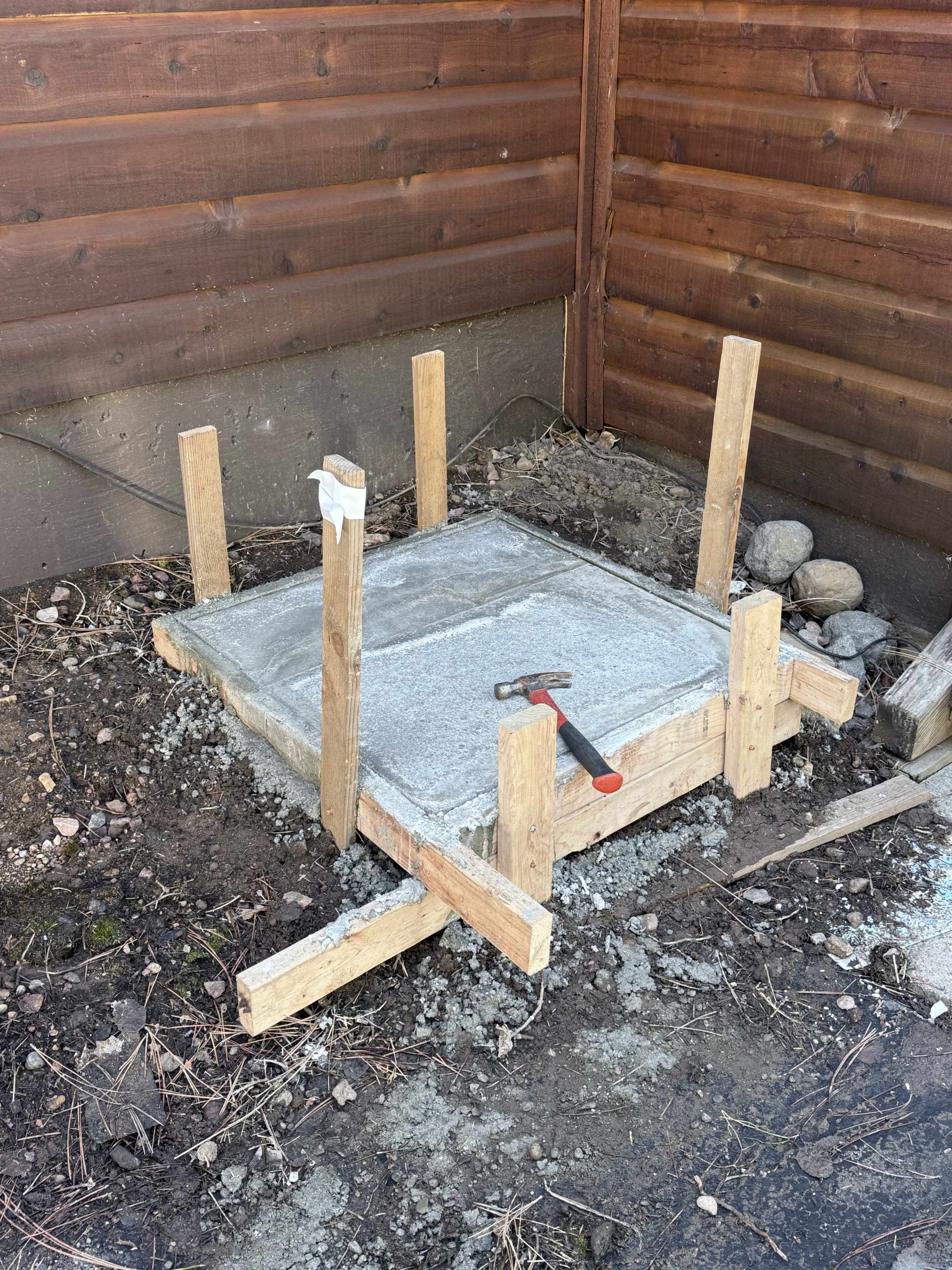 Freshly poured concrete heat pump equipment pad with wooden forms