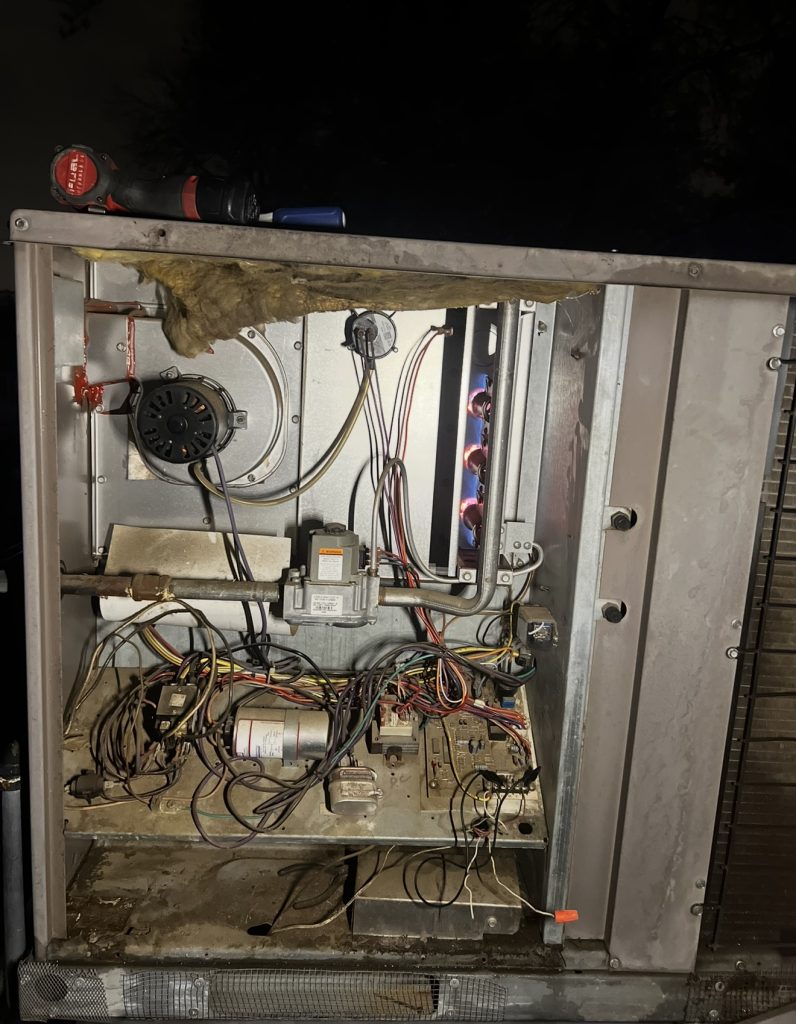 Heating unit with access panel removed and burners lit after flame sensor cleaning and pressure switch tubing replacement in Truckee